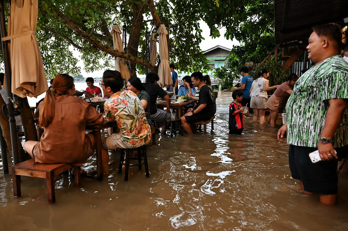 Ľudia húfne prichádzajú do zatopenej reštaurácie, aby sa najedli, sediac po členky vo vode